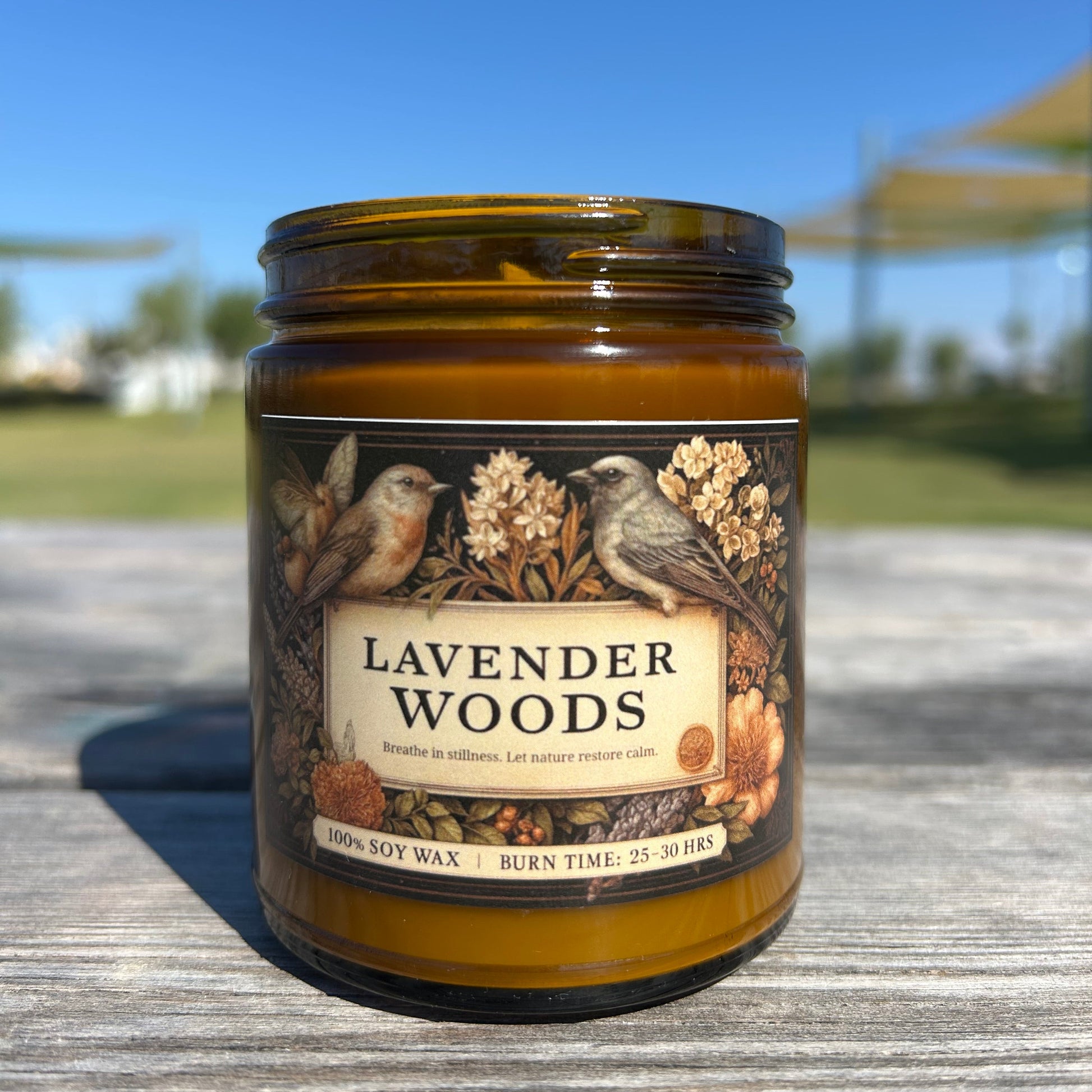 Jar of 'Lavender Woods' candle on a wooden surface with a blurred outdoor background